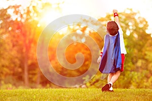 Confident little child boy plays superhero. Child with background of sunset sky.