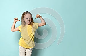 Confident little preschool girl posing in yellow t-shirt pointing with thumbs at herself.