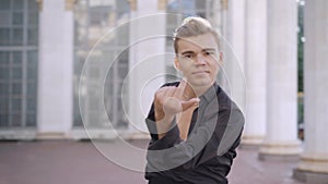 Confident male ballet dancer moving hands in sunrays looking at camera. Middle shot portrait of handsome young Caucasian