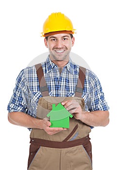 Confident male builder holding green house model