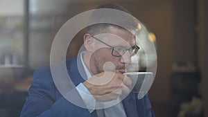 Confident male CEO drinking coffee in cafe. Portrait of successful Caucasian businessman enjoying break. Thoughtful man