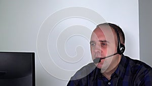 Confident male customer service representative with headset in front of computer