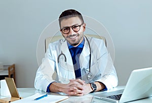 Confident male doctor smiling and looking at camera in the office.