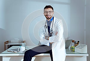 Confident male doctor smiling and looking at camera in the office.
