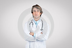 Confident male doctor with stethoscope standing with arms crossed