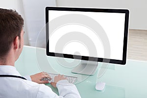 Confident male doctor working on computer at desk