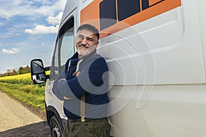 Confident male driver standing in front on his van and looking at camera