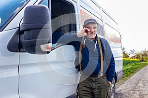 Confident male driver standing in front on his van and looking at camera