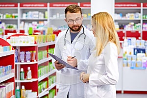 Confident male and female druggists talk in pharmacy