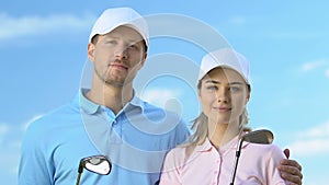 Confident male and female golfers posing with clubs, trainers of golf school