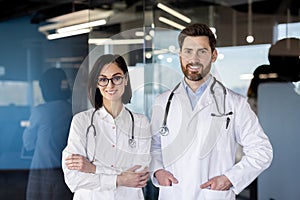 Confident male and female medical professionals posing in clinic corridor