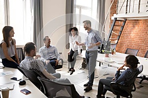 Confident male leader, coach talking with group of office workers