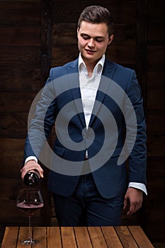 Confident male sommelier pouring wine to wineglass.