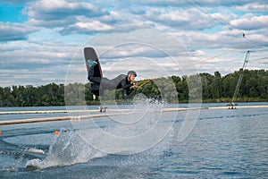 Confident male wakeboarder jumping over water surface on lake on summer day