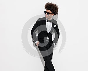 confident man with big curly hair holding hands in pockets and looking to side