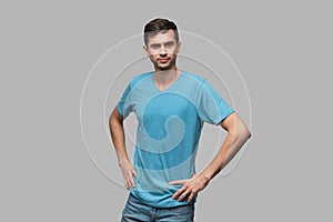 Confident man in a blue tee looking at the camera holding hands crossed. Concept of confidence