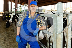 Confident man cow breeder standing in outdoor cowshed