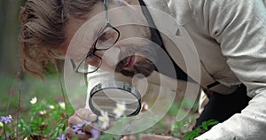 Confident man examining small flowers with loupe
