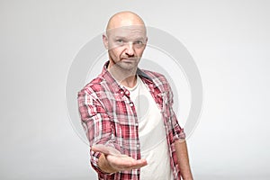 Confident man gives hand for handshake and looks at the camera with a serious expression on face.