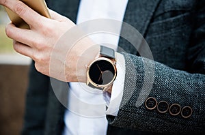 Confident man in gray jacket using smartphone, elegant business