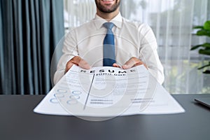 Confident man handing resume paper during job interview. Fervent
