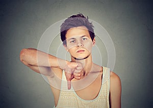 Confident man looking at camera giving thumbs down hand gesture