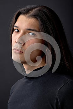 confident man model with long hair in black shirt looking at camera isolated over black