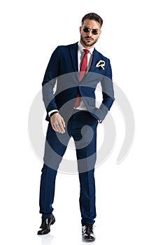 Confident man in navy blue suit with glasses holding hand in pocket