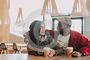 Confident man putting his arm on the shoulder of girlfriend and looking at her