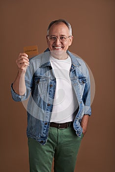 Confident man putting one hand into the pocket while showing his gold card