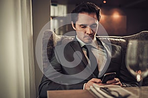 Confident man with smart phone in restaurant.