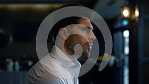 Confident man standing dark cafe hall profile. Scowling face expression closeup