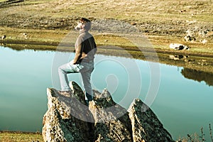 Confident man standing on the edge. Stunning view in the hilly landscape away from people. Tourist man relaxes in nature during