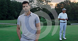 Confident man standing golf course outside. Two golfers relax at sunset field.