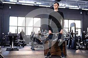 confident man in stylish sportswear holding barbell at sport center