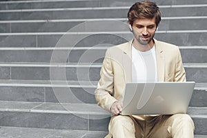 Confident man in suit using laptop for work on stairs