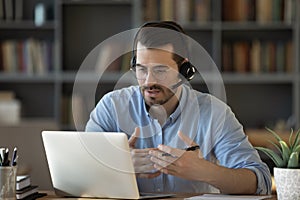 Confident man teacher wearing headset speaking, holding online lesson