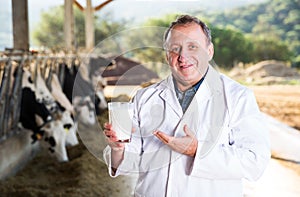 veterinarian approvingly demonstrating milk on dairy farm