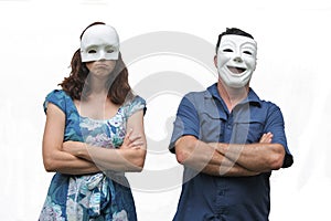 Confident man wearing a happy face mask standing beside a unconfident woman who wearing a sad face mask