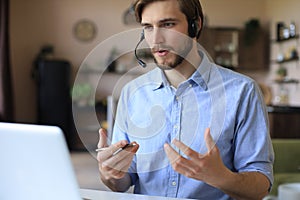 Confident man wearing headset speaking and watching business webinar training, listening to lecture