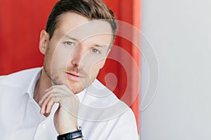 Confident man, white shirt, healthy skin, listens, red white background for your ad promo