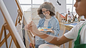 Confident man and woman artists, joyfully smiling and drawing together in a vibrant art studio