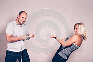 Confident man and woman pulling a rope