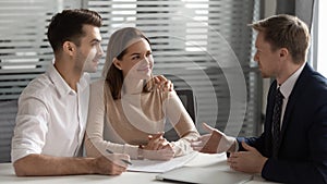 Confident manager consulting young couple about contract at meeting