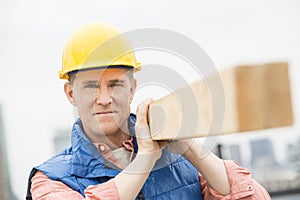 Confident Manual Worker Carrying Wooden Plank