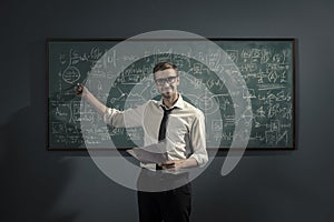 Confident math professor teaching in front of the chalkboard photo