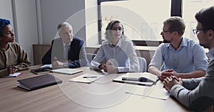 Confident mature business leader woman talking to diverse group