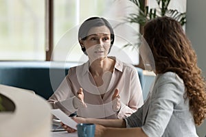 Confident mature business professional woman talking to younger female colleague