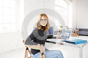 Confident mature businesswoman portrait while sitting at office desk smiling
