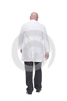 confident mature doctor in a white coat striding forward .